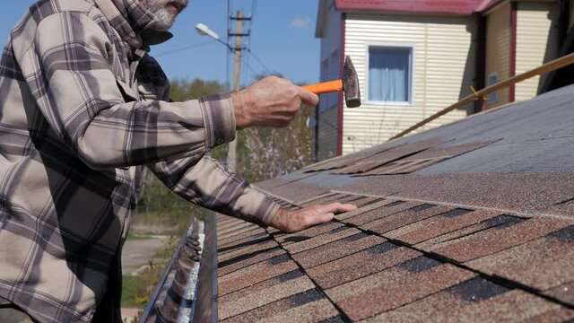 Laying of soft tiles. Bitumen roofing. Hammering nails with a hammer.