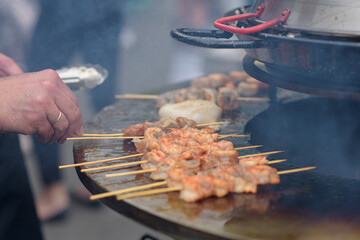 Cooking shrimp, prawn skewers on grill at street food festival - close up