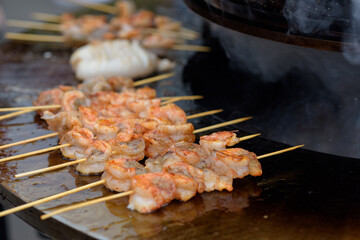 Cooking shrimp, prawn skewers on grill at street food festival - close up
