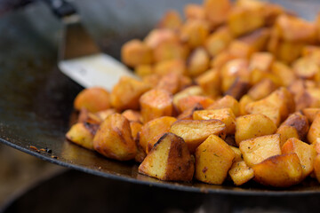 Chunks of fried potatoes in a large skillet during the street food festival.