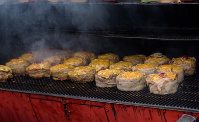 Handmade hamburger patties during the street food festival, smoke while cooking.