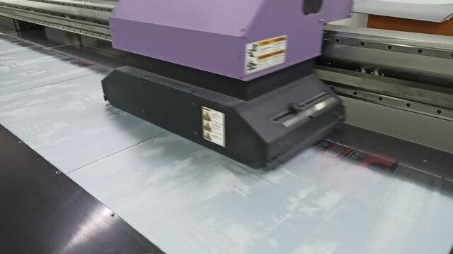 Ultra violet printer at work. Printing photos. Modern technology in action. Japanese printer Mimaki of ultra violet printing. Drawing on glass surface using ultra violet printing

