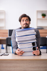 Young male employee unhappy with excessive work in the office