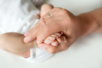 hands of parents. the legs of the newborn in the hands of mom and dad. baby's legs in his hands. 