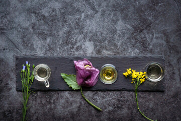 Agricultural oil products on a gray stone plate with flowers as a flat lay with poppy, flax and...