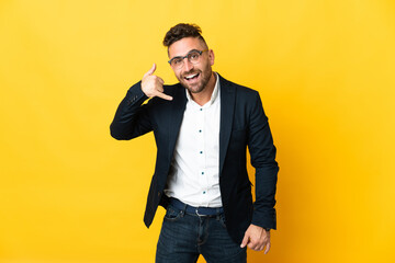 Businessman over isolated yellow background making phone gesture. Call me back sign