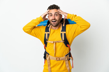 Young mountaineer man with a big backpack over isolated background with surprise expression