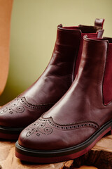 Burgundy leather chelsea boots made of genuine leather in classic style on a wooden cut. Close-up. High quality photo