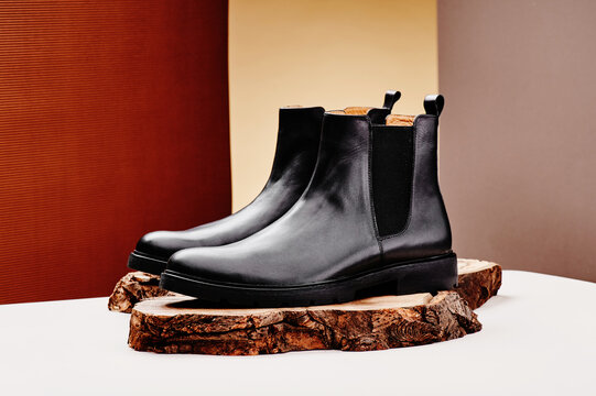Black leather chelsea boots made of genuine leather in classic style on a wooden cut. Close-up. High quality photo