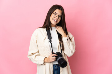 Young photographer Brazilian girl isolated on pink background laughing