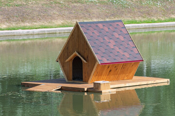 There is a house for swans on the lake in the water.