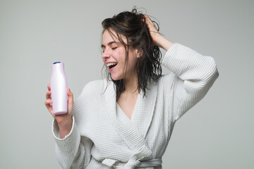 Woman touching her hair. Woman hold bottle shampoo and conditioner. Happy young woman with balm...