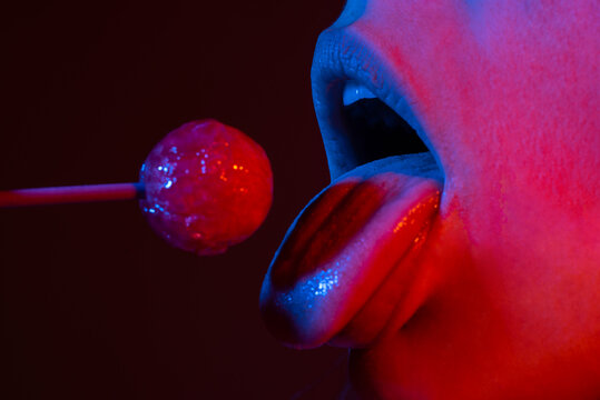 Close up lips with lollipop isolated, sexy blowjob, sensual mouth with lipstick eats sweets. Sexy design for women and girls. Beauty lips on neon lights. Night club background.