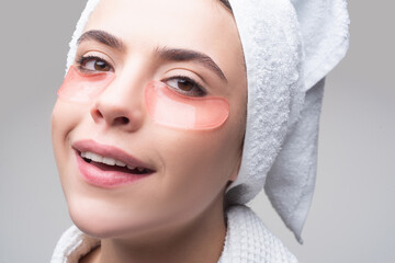 Close up portrait girl with towel on head. Portrait of beauty woman with eye patches showing an effect of perfect skin. Brunette spa girl. Eyes mask cosmetic patches woman face closeup.