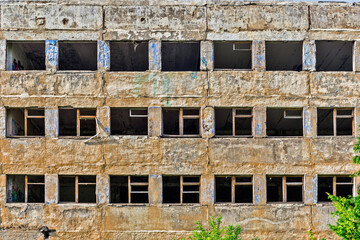 concrete wall of a ruined house with broken windows