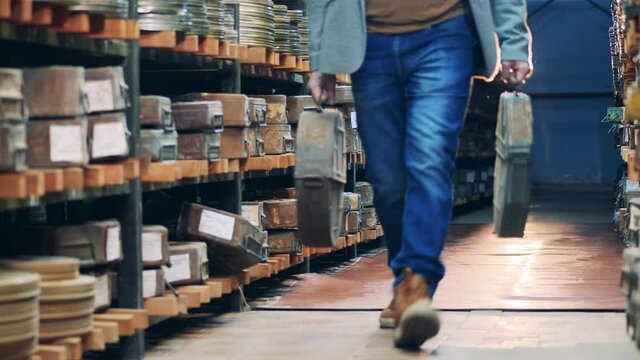 Archivist is carrying large cases with vintage tape films