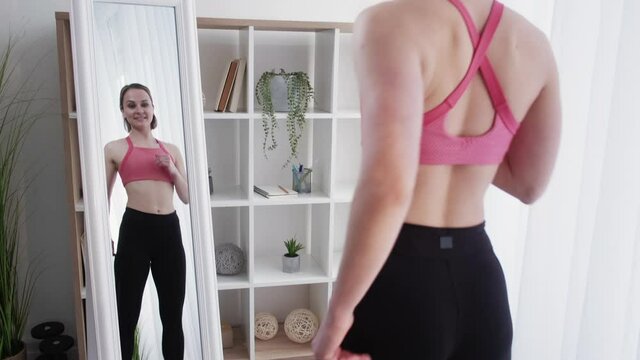 Dance workout. Cardio exercise. Zumba class. Home fitness. Body fat burn. Joyful young sporty woman in activewear practicing at mirror in light room interior.