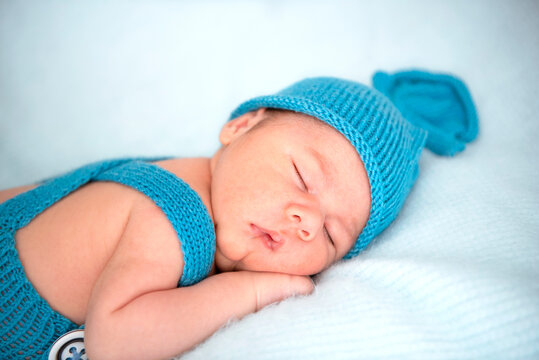 Sleeping newborn baby boy in blue hat and costume. Close up. Copy space.