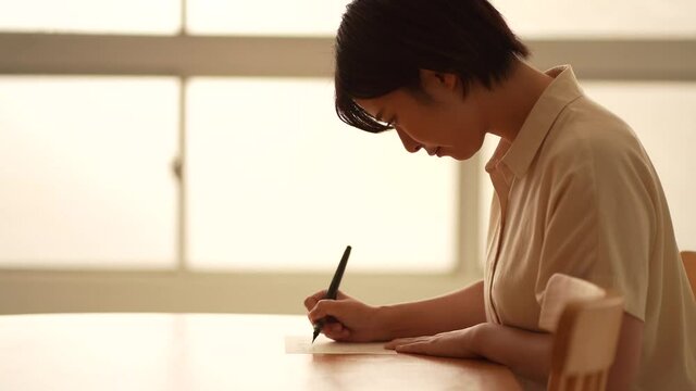 筆ペンで手紙を書く女性