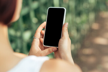 Girl holding smartphone while walking in the park with copy space