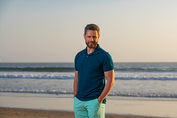 Fototapeta na wymiar Portrait of man on beach. Portrait of middle aged man with a serious expression and ocean backdrop standing at the beach.