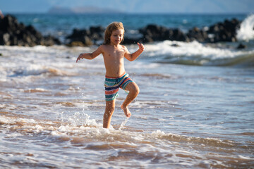 Fototapeta na wymiar Active little boy splashing in the sea waves on a summer day during the holidays. The concept of family holidays with children.