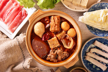 Personal spicy hot pot with pork, tofu,  mushrooms and green leaves 