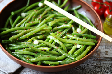 Selective focus. Green beans with spices in a bowl. Vegan food. Healthy lunch.