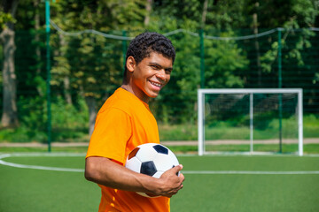 African-American man holding soccer ball while standing on sports court
