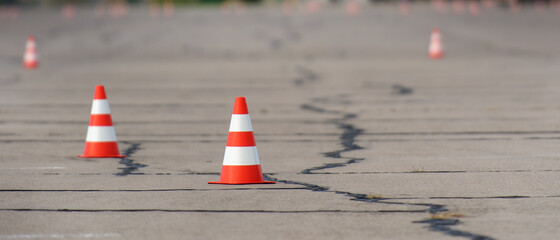 Banner view of bright orange traffic cones ready for slalom on an asphalt surface.
