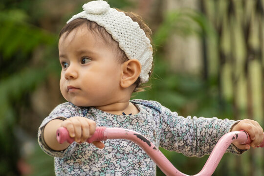 Cute toddler child, boy, playing with tricycle in park and eating apple, kid riding bike on sunset