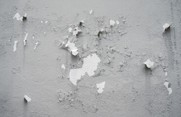 Peeling paint on gray concrete wall. Peeling, cracking, or blistering paint occurs when there is a loss of adhesion between the paint and the surface it's placed on.