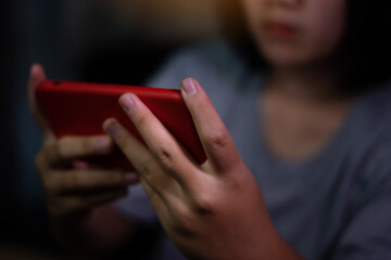 Asian girl using smart phone or mobile playing games on sofa at home. Young woman using mobile phone on sofa at night. Mobile addiction or insomnia. Young people is phone addiction problem.