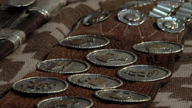 Old Coins and Metal Ornaments Mounted in an Argentine Gaucho Belt called "Rastra" on a Table. Close Up.  
