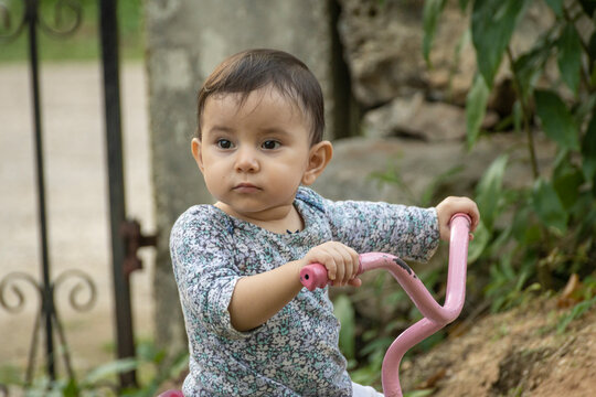 Cute toddler child, boy, playing with tricycle in park and eating apple, kid riding bike on sunset