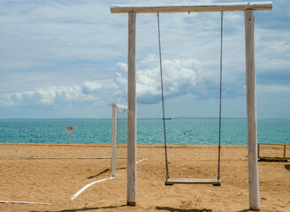Wooden swing on the beach near the sea.