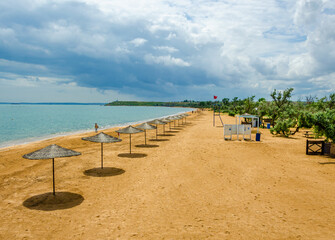 A row of umbrellas from the sun on the beach near the sea.