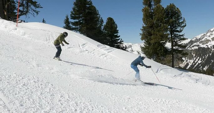 Male and Female pro skier showing nice downhill ski turns in wonderful snowy mountain landscape in the alps. Friends skiing cinematic ski turns on a steep ski slope in a austrian ski resort. 4K