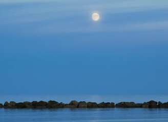 Luna sul mare sopra gli scogli al tramonto