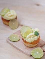 Lemon cupcake with slice of lime on white plate.