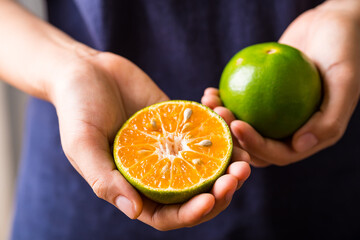 Close up of green tangerine orange fruit holding by woman hand, Healthy eating