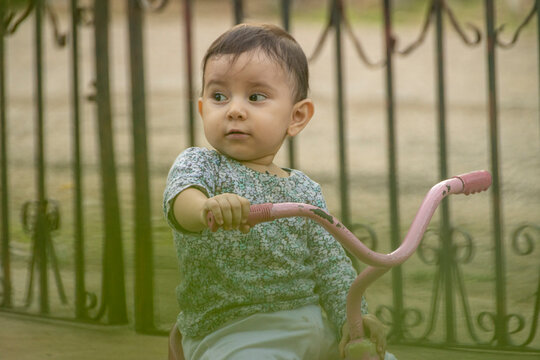 Cute toddler child, boy, playing with tricycle in park and eating apple, kid riding bike on sunset