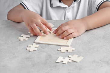 Asian little boy playing wooden jigsaw puzzle