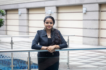 An Indian woman standing with her arms crossed in an urban corporate setting. Corporate female employee in smart formal attire