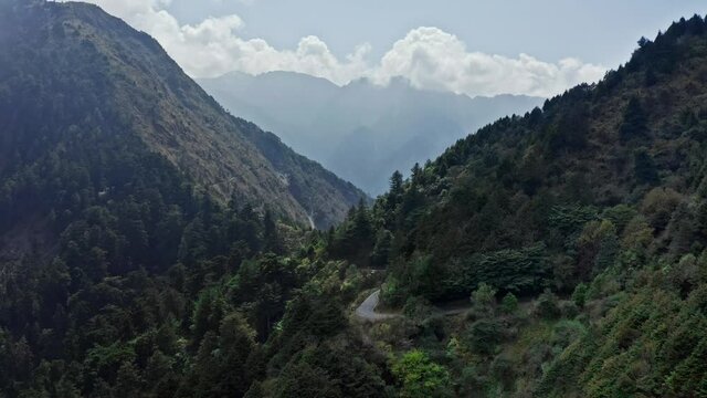 Epic aerial shot of Yushan Yu Shan Mountain in Taiwan during sunny day with clouds in background.