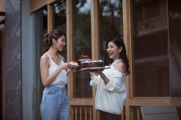 Two pretty young women enjoying coffee and cake together in a coffee house sitting at a table laughing and gossiping with happy smiles.