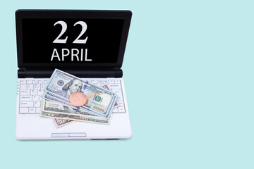 Laptop with the date of 22 april and cryptocurrency Bitcoin, dollars on a blue background. Buy or sell cryptocurrency. Stock market concept.