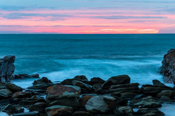 Rocky Sunrise at the seaside with cloud cover and headland