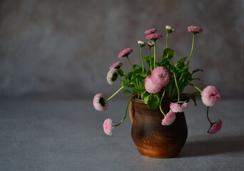 Pink daisies in a brown clay mug.