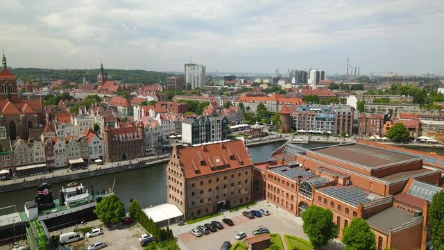 Polish Baltic Frederic Chopin Philharmonic and Hotel KROLEWSKI courtyard with many cars parked near the buildings, Nova Motlawa riverbank in Old Town Gdansk, Poland on a cloudy day